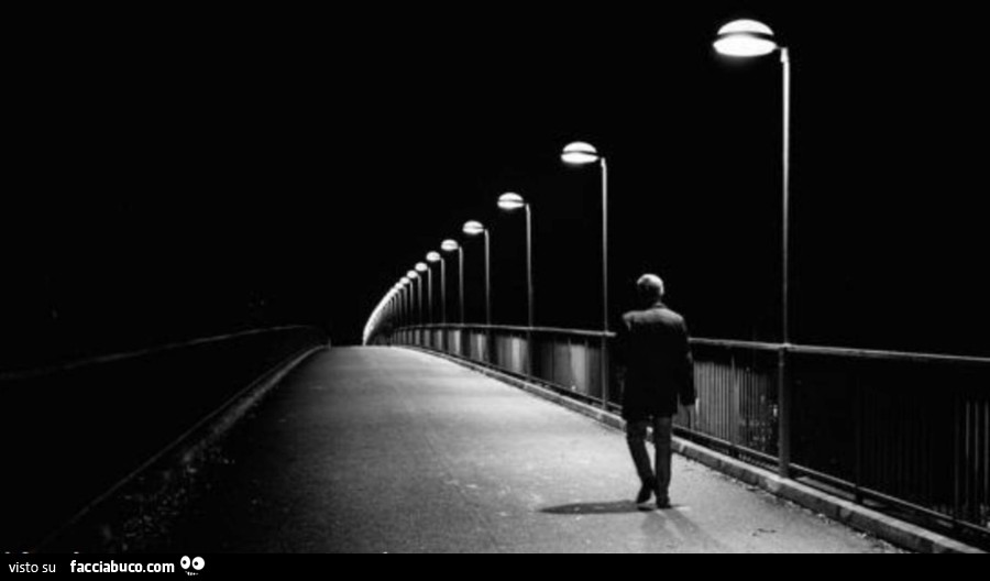 Signore cammina su ponte illuminato dai lampioni